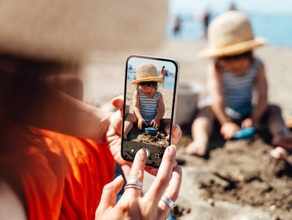 Una mujer fotografía a su hija en la playa.