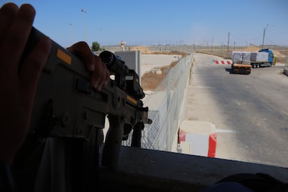 Un militar vigila dos camiones cargados de alimentos a su partida de Israel, en el paso de Kerem Shalom. 