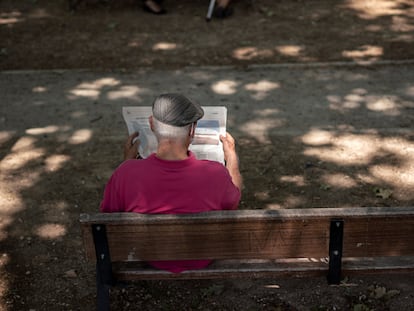 Un hombre lee un periódico en un parque de Madrid.