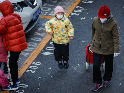 Un niño y una mujer con mascarillas a la salida de un colegio en Pekín, este jueves.