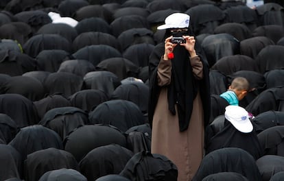 Una mujer usa su teléfono móvil para filmar a manifestantes durante una concentración que exige la destitución del Presidente Ali Abdullah Saleh de Yemen.