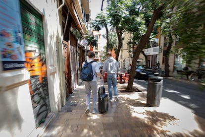 Dos turistas recorren con sus maletas el casco antiguo de Valencia.