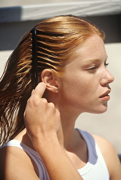 Young woman combing her hair, outdoors