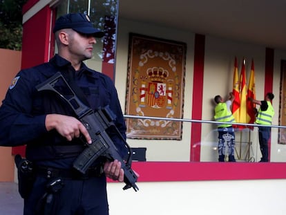 Un policia vigila la tribuna del desfile de la Fiesta Nacional mientras dos operarios ultiman los preparativos.