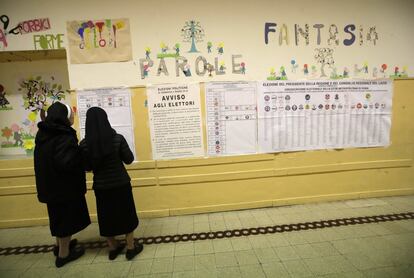 Dos monjas observan los candidatos que concurren a las elecciones en un centro electoral cercano al Vaticano.