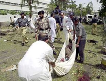 Miembros de los servicios de emergencia trasladan el cadáver de una de las víctimas mortales del atentado de ayer en Karachi.