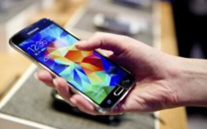 Una mujer sostiene en su mano un tel&eacute;fono inteligente Samsung Galaxy S5. 