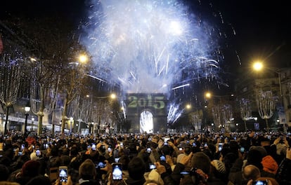 Centenas de pessoas tiram fotografias dos fogos de artifício sobre o Arco do Triunfo na celebração de Ano Novo na Avenida Champs-Élysées em Paris, França.