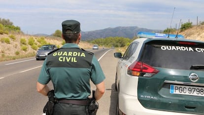 Un agente de la Guardia Civil, junto a un vehículo patrulla, en una imagen de archivo.