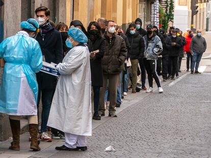 Personal sanitario atiende a personas haciendo cola para una PCR frente al centro de salud Universidad en Malasaña (Madrid).