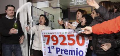 El dueño de la administración de loteria de Saldaña (Palencia) brinda con varios vecinos a las puertas de su establecimiento donde se ha vendido el número 79.250