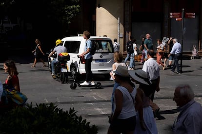 Un conductor de patinete comparte espacio con motos, vehículos y peatones.