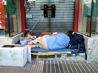 Dos personas, duermen al raso en la calle Alcalá de Madrid.