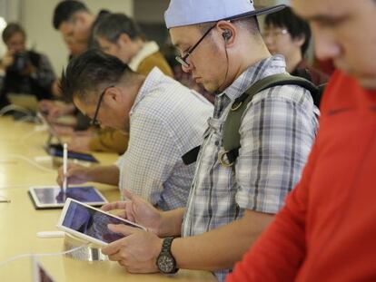 Clientes de una tienda de Apple probando sus tabletas iPad.