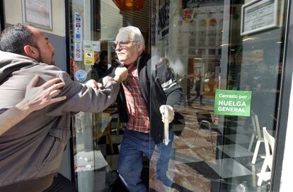 Un miembro de un piquete agarra por el cuello a un hombre durante una discusi&oacute;n en la entrada de un comercio de Valencia.