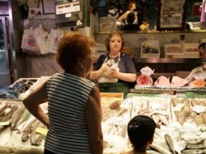 Abuela comprando mientras se ocupa de su nieto.