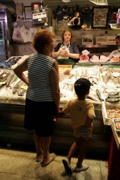 Abuela comprando mientras se ocupa de su nieto.