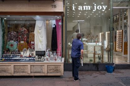 Un hombre limpia el escaparate de un comercio del centro de Sevilla.