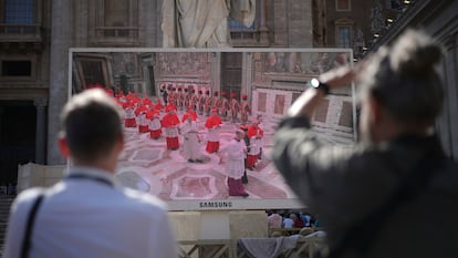 Fieles observan en una pantalla gigante, instalada en la plaza de San Pedro, la entrada de los cardenales a la Capilla Sixtina.