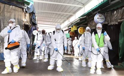 Trabajadores con trajes de protección desinfectan un mercado en Bupyeong, Corea del Sur, este lunes.