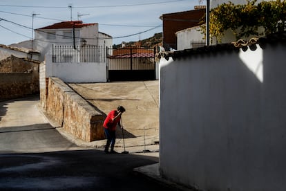 Una mujer barre la calle en un pueblo de Cuenca.