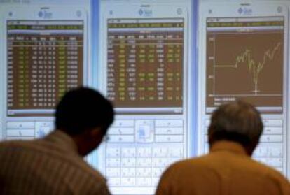 Dos inversores indonesios observan un tablero electrónico con los índices de la Bolsa de Yakarta, Indonesia.