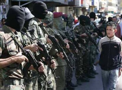 Un joven palestino pasa delante de milicianos de Al Fatah desplegados en la ciudad de Ramala, en Cisjordania.