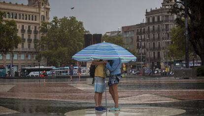 Una pareja bajo la lluvia y bajo una sombrilla en la plaza de Cataluña.