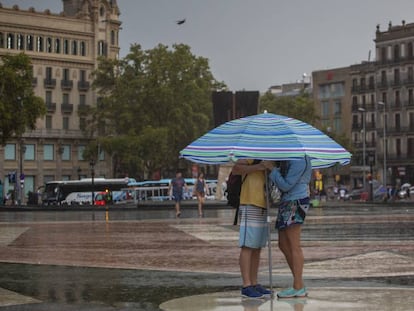 Una pareja bajo la lluvia y bajo una sombrilla en la plaza de Cataluña.