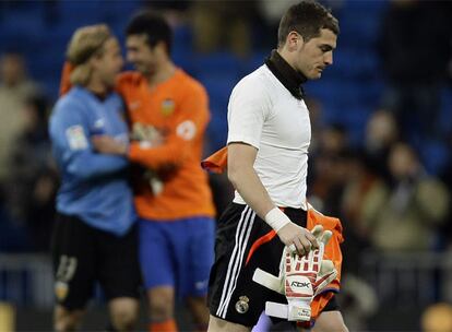 Casillas se retira cabizbajo al final del partido mientras Hildebrand y Albiol, al fondo, celebran el triunfo del Valencia en el Bernabéu.