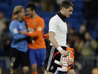 Casillas se retira cabizbajo al final del partido mientras Hildebrand y Albiol, al fondo, celebran el triunfo del Valencia en el Bernabéu.