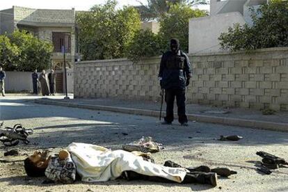 Un policía iraquí contempla el cadáver de un insurgente muerto ayer en una explosión en Bagdad.