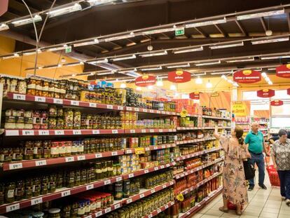 Varios consumidores compran alimentos en un supermercado. 