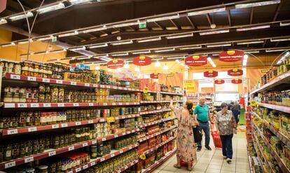 Varios consumidores compran alimentos en un supermercado. 