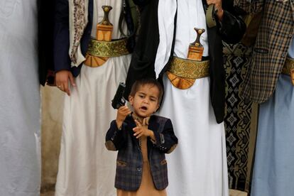 Un niño sostiene una pistola de su padre mientas asiste a una reunión de tribus leales al movimiento Houthi para mostrar su apoyo, en la ciudad yemení de Saná.