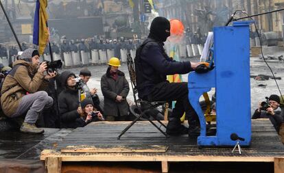 Un activista enmascarado de la oposicin contra el gobierno toca un piano situado en una barricada en Kiev, durante un concierto organizado por los activistas y para los policas.