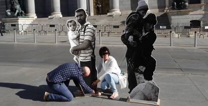 Miembros de Amnist&iacute;a Internacional colocan frente al Congreso varias im&aacute;genes de refugiados, este martes.