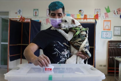 Un ciudadano sostiene a un perro mientras deposita su voto en una urna en Santiago.