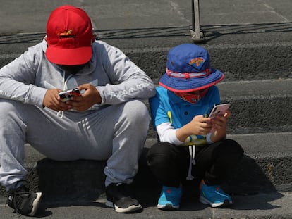 Un par de niños se entretienen con sus teléfonos celulares, en Ciudad de México.