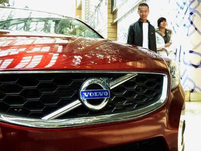 Dos ciudadanos chinos pasan delante de un coche marca Volvo en un centro comercial de Pekín.