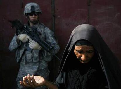 Un soldado estadounidense observa a una mujer, ayer, en una calle de Bagdad.