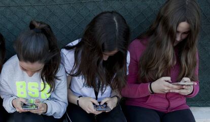 Tres amigues adolescents amb el mòbil.