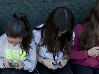 Tres amigues adolescents amb el mòbil.