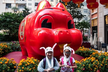 Duas crianças posam em frente a uma estátua de um porco gigante em Hong Kong.