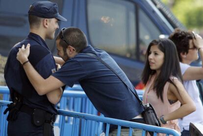 Un joven se abraza a un policía que vigila a los concentrados en la Puerta del Sol.