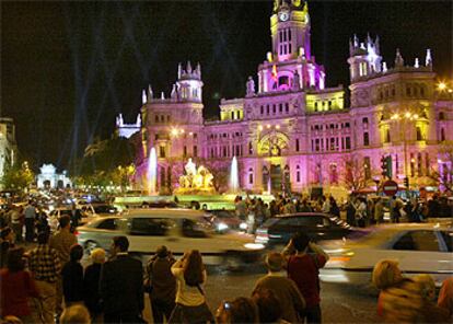 Decenas de viandantes se agolpan ante la fuente de la Cibeles para ver la iluminación nocturna especial con motivo de la boda real.