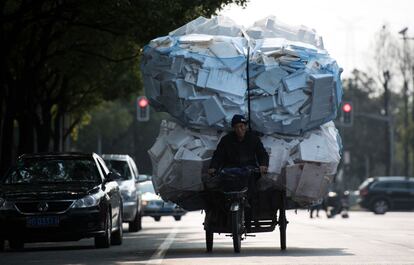 Un hombre circula en su triciclo cargado de cajas de poliestireno por una calle de Shangái, China.