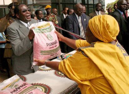 El presidente de Zimbabue, Robert Mugabe, entrega un saco de maíz a una simpatizante de su partido hoy en Harare