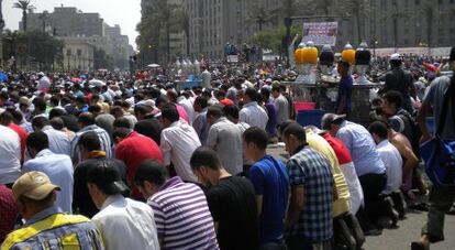 Miles de personas rezan durante una manifestación en la plaza; al fondo, la Mugamma.