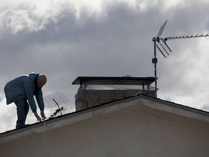 Un hombre cambia una antena antigua en una vivienda de Madrid.